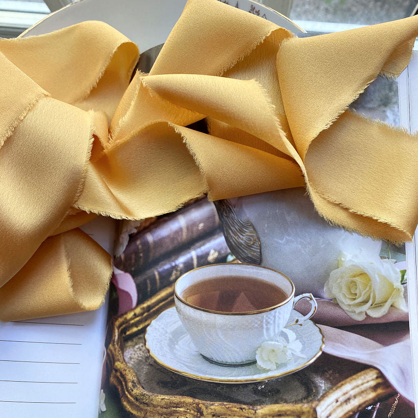 Luxurious silky ribbon in Lumière Dorée evoking sunlight and warmth. 1½" wide × 25 yards, soft and supple, perfect for gift wrapping, couture projects, and decorative accents.