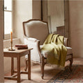 Handwoven baby alpaca throw draped over antique French fauteuil in leaf green