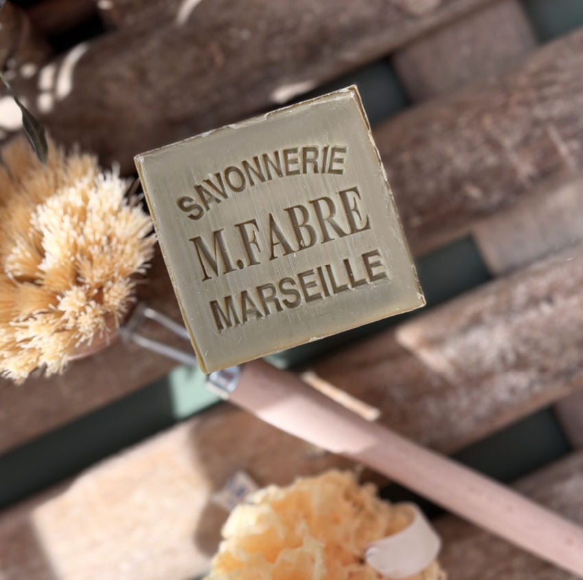 Bar of soap with &#39;Savonnerie M. Fabre Marseille&#39; branding on a wooden surface.