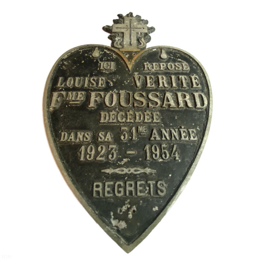 Close-up of raised lettering and “Regrets” inscription on heart-shaped plaque