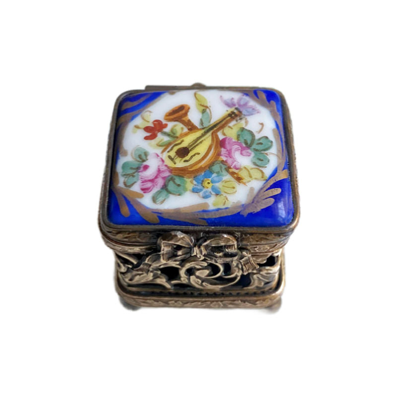 Top detail of hand painted Limoges blue box with gilt bow closure, musical instruments and roses 