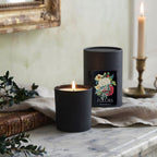 Noël en Fleurs luxury candle with FrenchGardenHouse gift box displayed on a marble mantel with French book and boxwood greenery