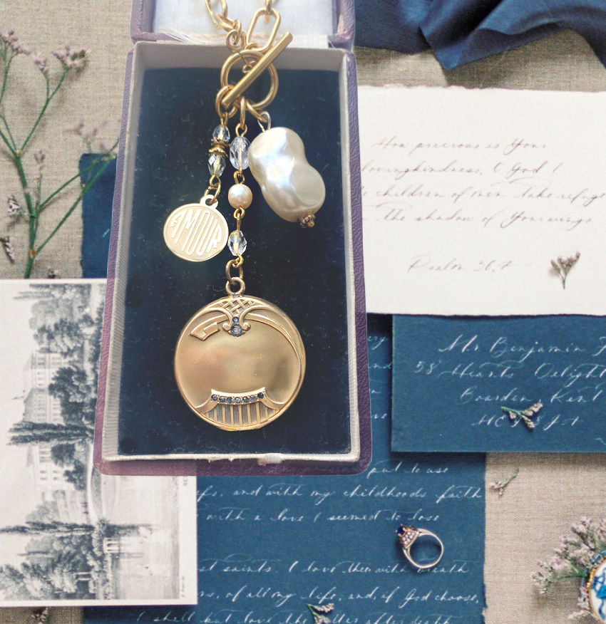 A gold  necklace featuring a gold-filled locket with paste stones, a pearl dangle, and a gold-plated charm, on a chunky paper clip chain.