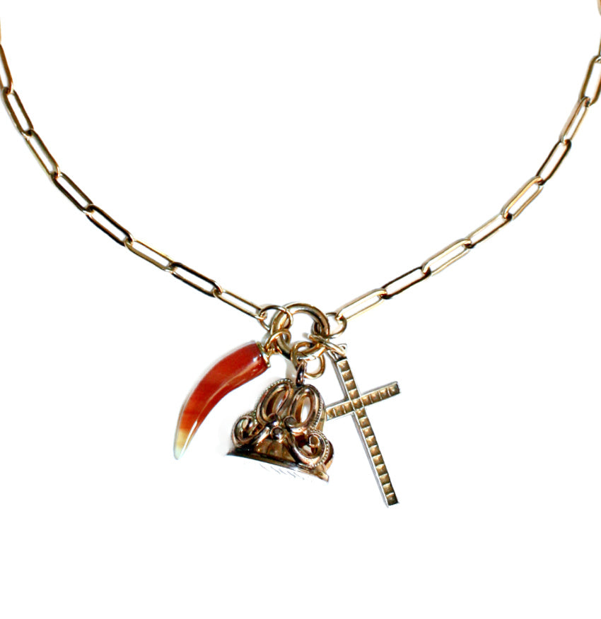 A gold necklace featuring an antique gold monogrammed watch fob, a Victorian agate charm set in gold, and a gold-filled cross, displayed on a white background.