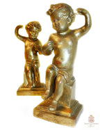 A charming pair of antique Italian Florentine gilt wood cherubs or putti on pedestal bases, beautifully aged with warm patina and red bole showing through the original gilding.