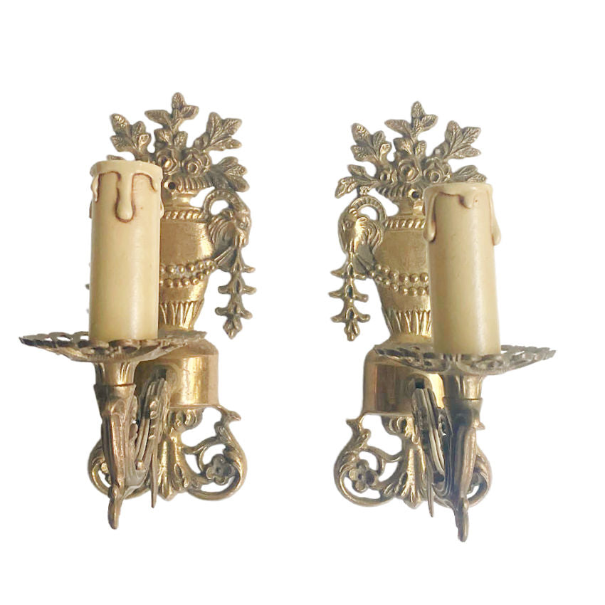 A pair of antique French bronze floral urn single light wall sconces with classical styling, featuring tall urns topped with roses, ram heads, and swagging garlands