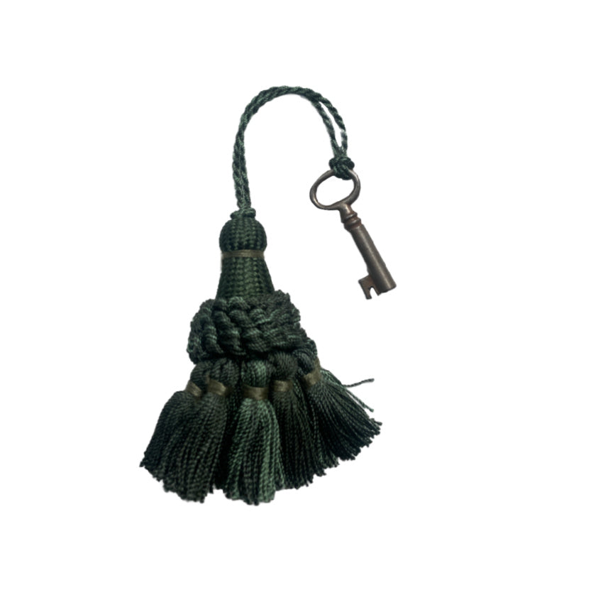 Small green French tassel with antique desk key, charming woven threads and authentic patina—an elegant decorative accent for French country styling.