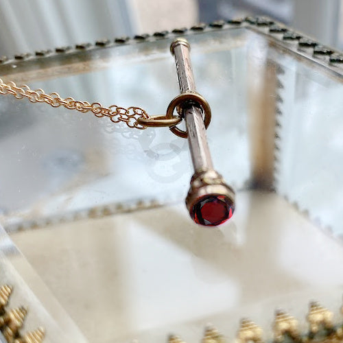 Antique gold chatelaine pencil necklace with red garnet cap, detail of red stone.