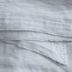 Close view of ocean blue-green linen fabric texture showing soft weave and gently frayed edge