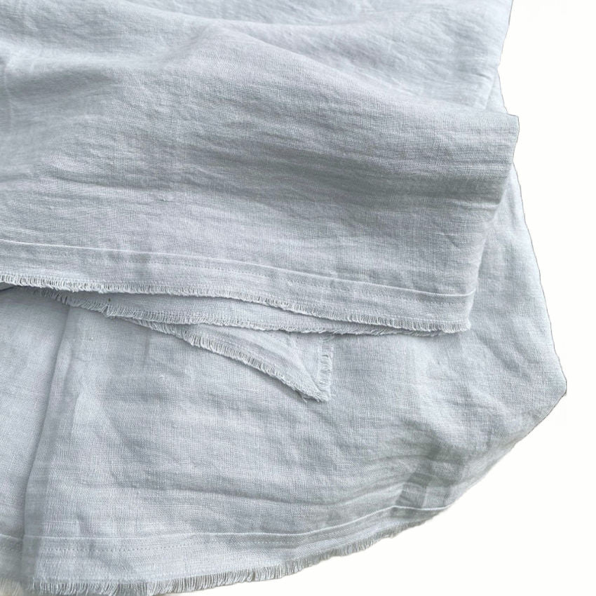 69x69 inch linen tablecloth in airy ocean hue with frayed edge detail styled for relaxed summer table setting