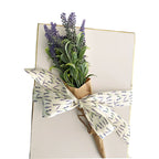 Gift box tied with satin white ribbon with lavender flowers on it, tied with a bundle of French dried lavender.