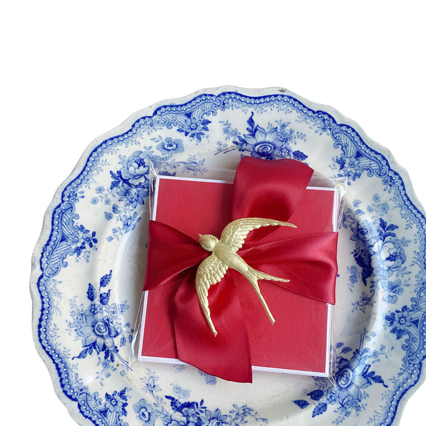 Red place card with gilded bird and silk ribbon