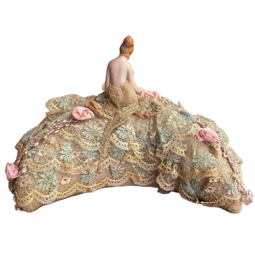 collectible bisque doll with delicate painted face and lace trimmed half moon cushion base back view