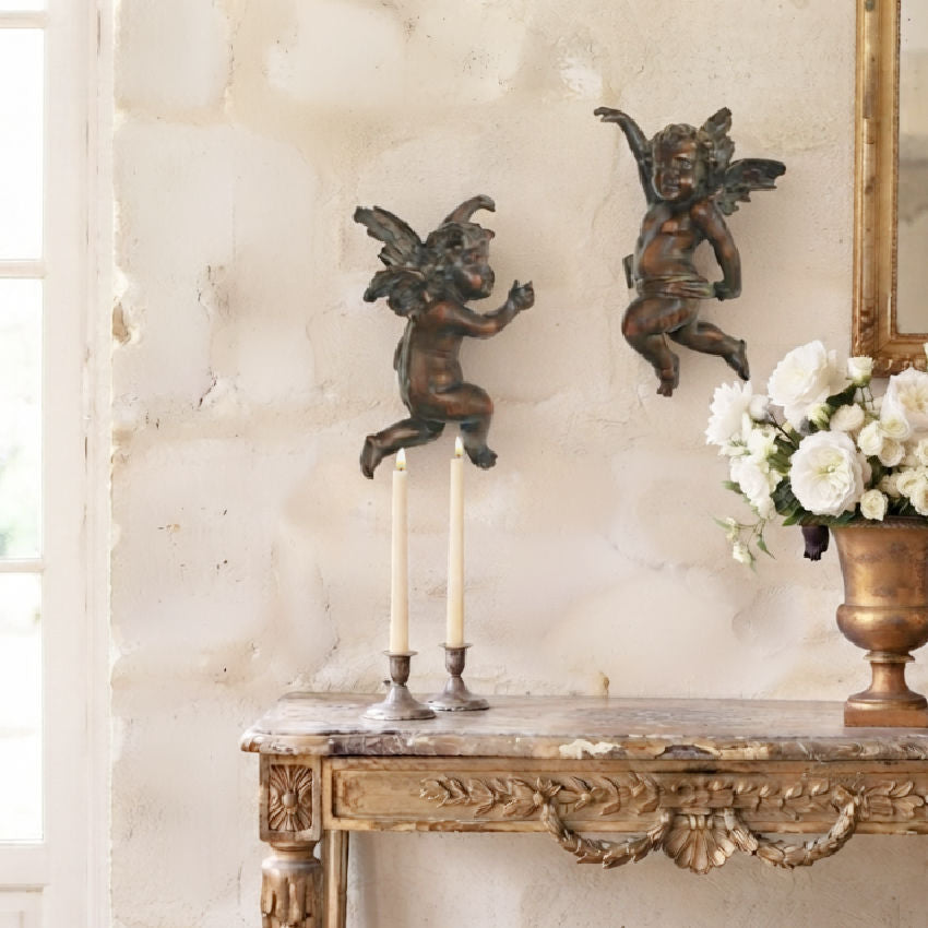 Pair of antique Italian Baroque angels displayed above a gilded console in a European interior