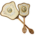 Exquisite hand-painted vanity mirror and brush set with gilt filigree and romantic courting scenes. A rare and elegant treasure for the antique dressing table.