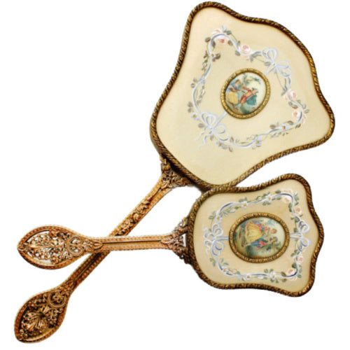 Exquisite hand-painted vanity mirror and brush set with gilt filigree and romantic courting scenes. A rare and elegant treasure for the antique dressing table.