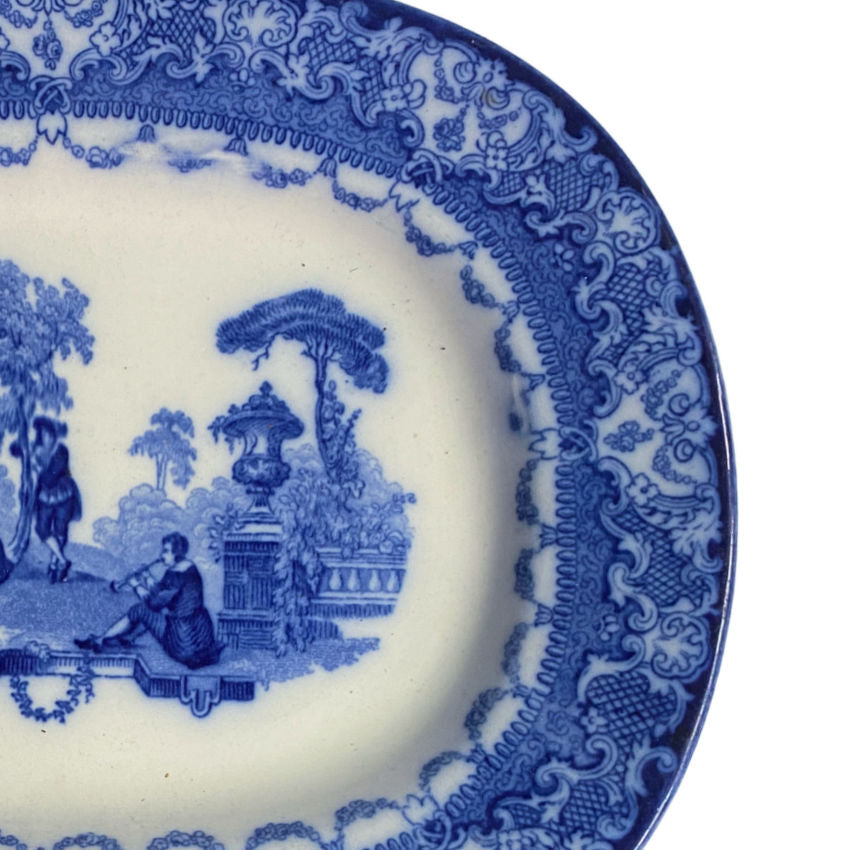 Antique oval platter, sFlow Blue   1900 English transferware with ornate central scene of minstrel and lovers in a garden setting and ornate floral borders