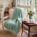 Handwoven sea glass alpaca throw draped over linen chair in French country living room with soft natural light