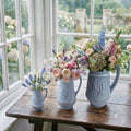 Set of three antique European decorative pitchers in French Country sun room filled with roses.