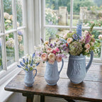 Set of three antique European decorative pitchers in French Country sun room filled with roses.