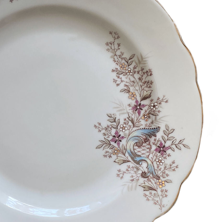 Detail close up of hand painted antique French plates with romantic floral scrollwork and gold accents