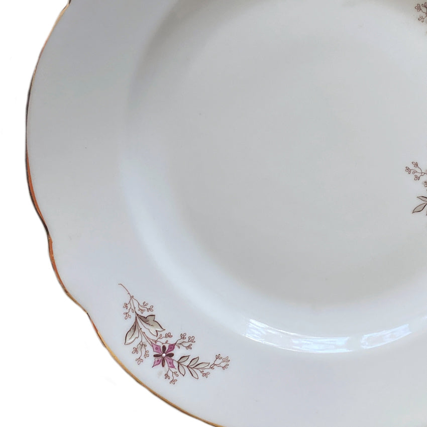close detail of hand painted flowers raised enamel and gilded rim on antique porcelain plate