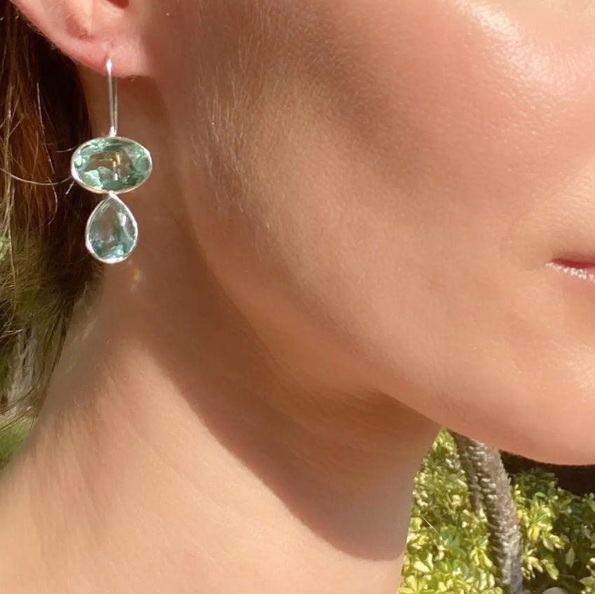A pair of gold-plated earrings featuring emerald-cut sky blue quartz gemstones with a bezel set and teardrop dangle design.