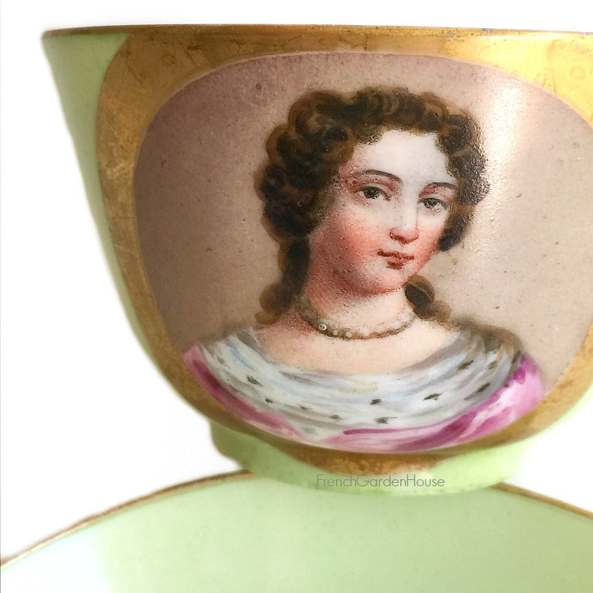 Close up of an antique French Sevres Vieux Paris porcelain tea cup in rare apple green , hand-painted with a delicate female portrait and gilt accents. She is wearing a pink gown and an ermine collar. A charming collectible from a European estate, perfect for antique French porcelain enthusiasts.