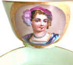 Close up of Antique French Vieux Paris Sevres porcelain tea cup and saucer in  hand-painted with a portrait of a woman wearing a pink hat and necklace with curly hair. 
