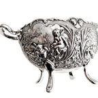 Close-up of cherubs reading a book and floral relief on vintage silver plated bowl
