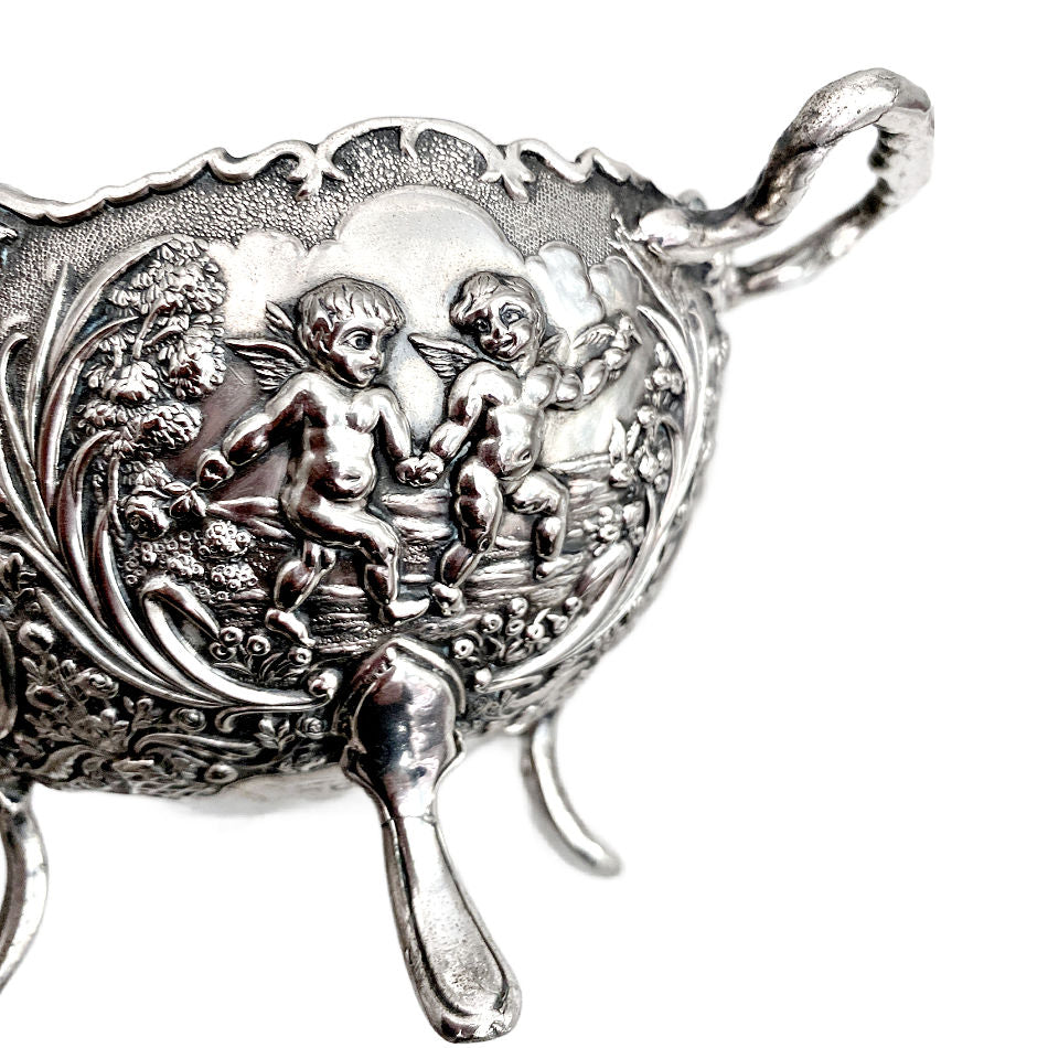 Close-up of cherubs and floral relief on vintage silver plated bowl