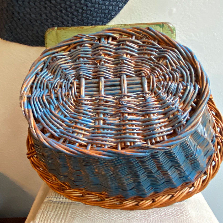 Handwoven vintage Dutch wicker basket close-up showing faded Delft painted finish and tactile weave texture bottom.