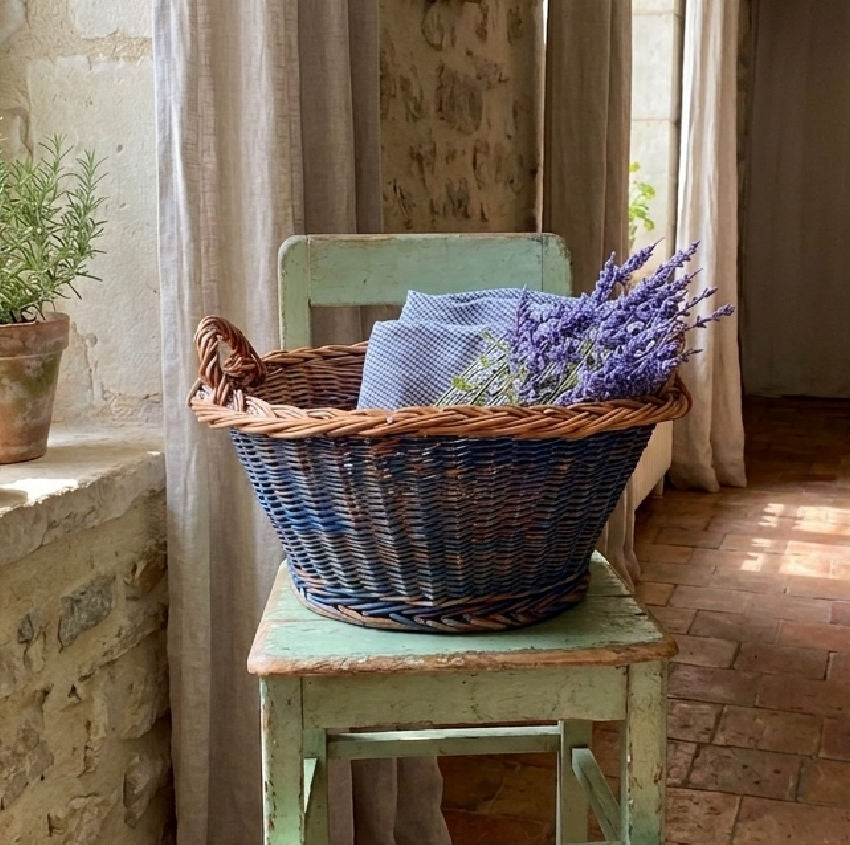 Vintage Dutch faded Delft painted wicker basket styled with antique linens and lavender on an antique chair