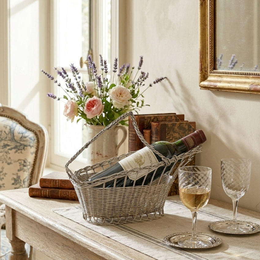 Vintage French metal wine carrier with twisted handle on side board with glasses and antique books in French Country living room