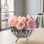 Vintage silver plated cherub and floral footed bowl styled with miniature roses on a cream table in a Paris apartment