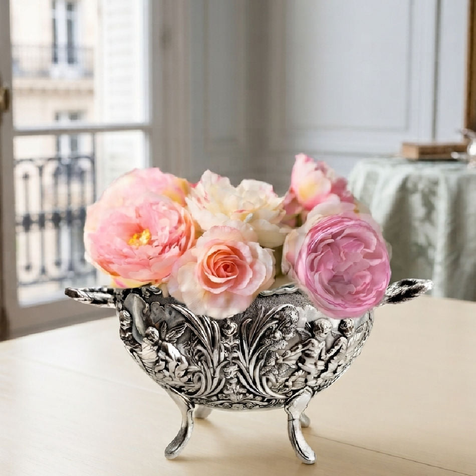 Vintage silver plated cherub and floral footed bowl styled with miniature roses on a cream table in a Paris apartment