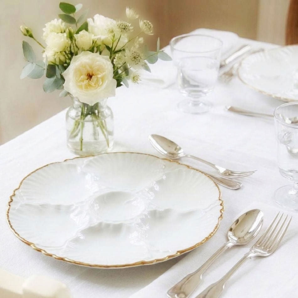  Belgian Porcelaine de Baudour oyster plate in white porcelain with gold edges, styled on an elegant dining table with antique silver and fine white linens.