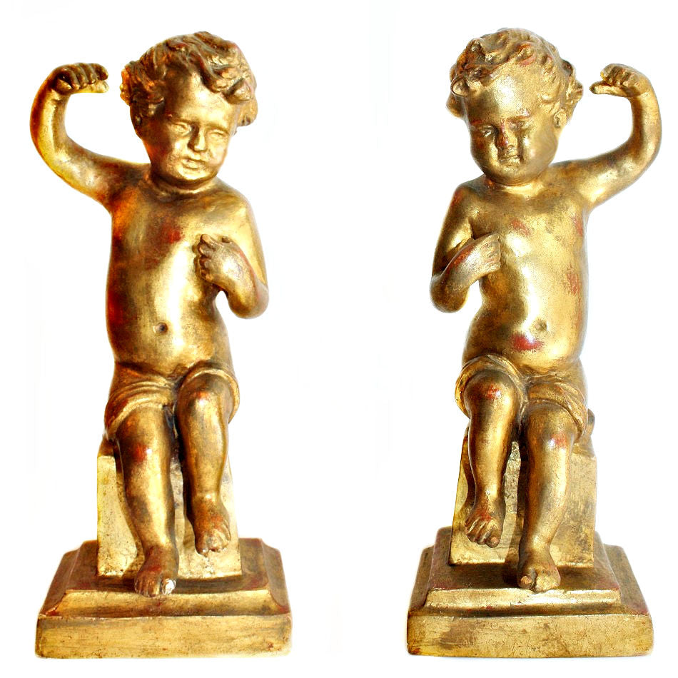 A pair of antique hand-carved gilt wood putti or cherubs standing on square bases, with gold leaf finish and showing signs of age-related wear.