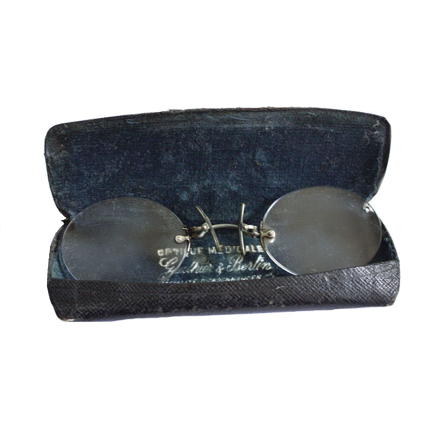 Antique French Pince-Nez eyewear in white glasses with a metal frame, displayed next to their original leather-covered case with Optique Medicale inscription.
