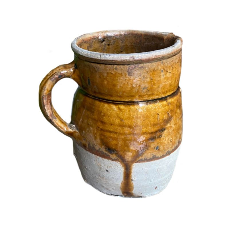 Antique French country pottery pitcher with a golden caramel and brown glaze, with an uneven and glaze-free bottom.