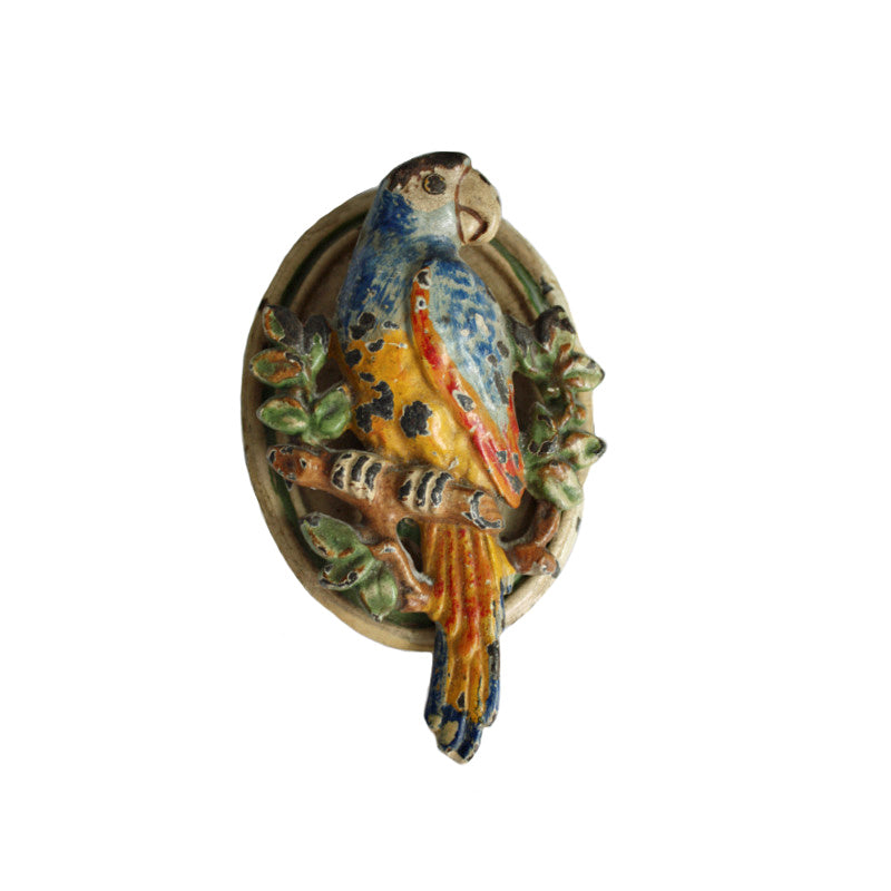 Antique cast iron door knocker shaped like a parrot with bright multicolored paint, showing signs of wear and aging.