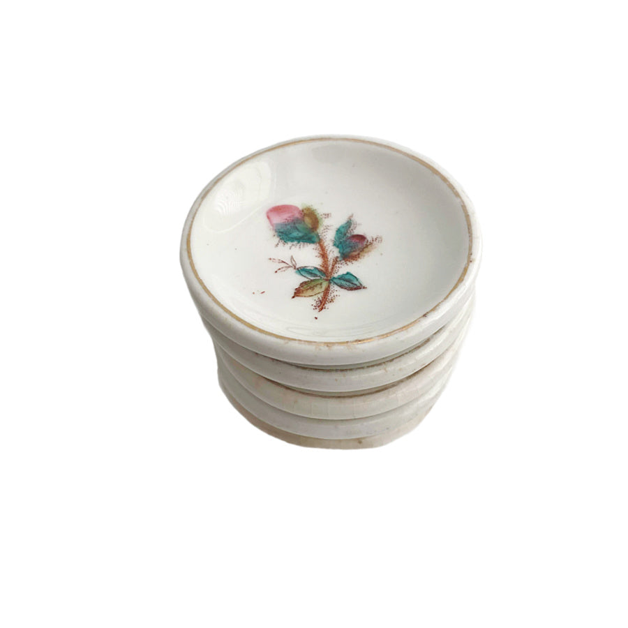 A set of five antique ironstone butter pats with a pink moss rose design.