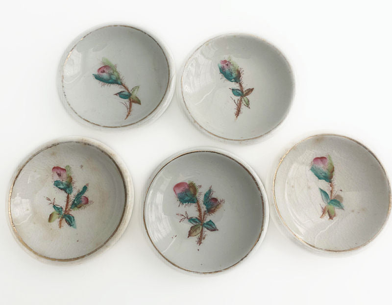 A set of five antique ironstone butter pats with a pink moss rose design.