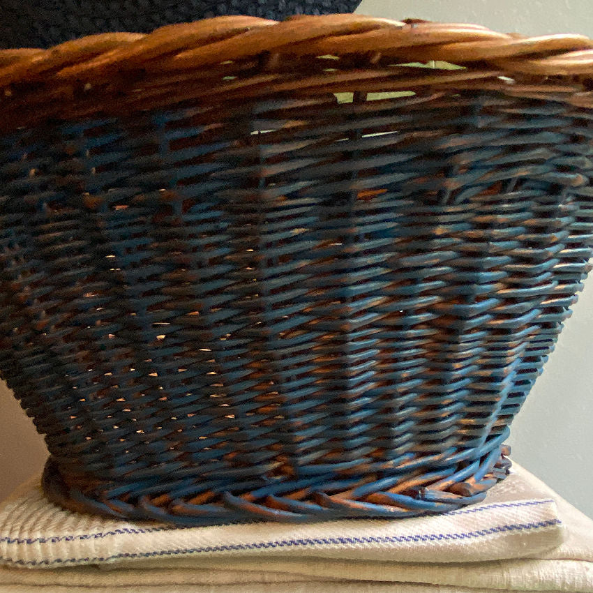 Handwoven vintage Dutch wicker basket close-up showing faded Delft painted finish and tactile weave texture