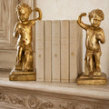 Antique Baroque giltwood putti sculptures on pedestal bases with antique cream books on an antique French COntry mantel