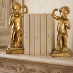 Antique Baroque giltwood putti sculptures on pedestal bases with antique cream books on an antique French COntry mantel
