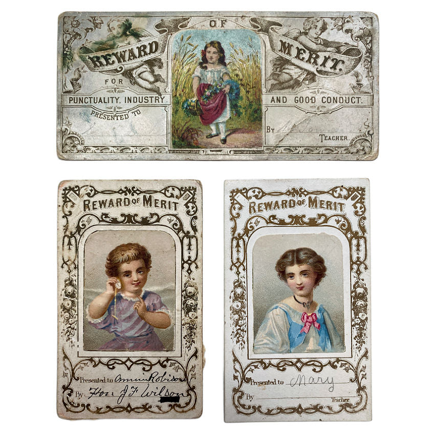 Three vintage &#39;Reward of Merit&#39; cards featuring children on a white background