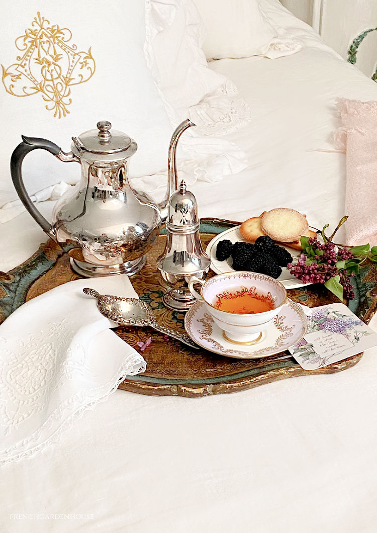 Tea with lilacs on a white linen bed